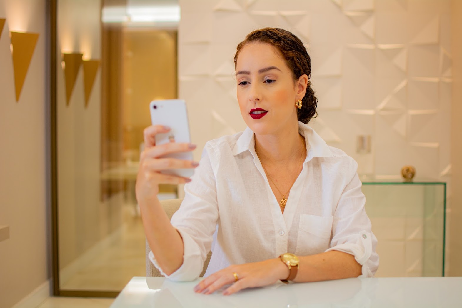 Thais Pavan usando o celular em um ambiente profissional