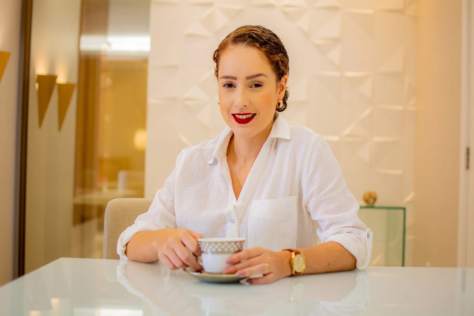 Thais Pavan com uma xícara em um ambiente profissional